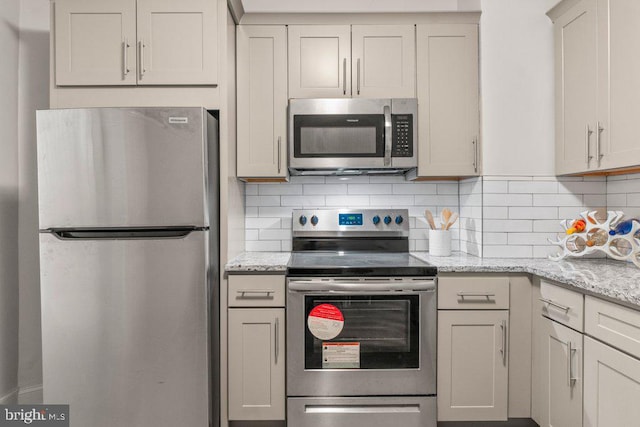 kitchen with tasteful backsplash, light stone countertops, and appliances with stainless steel finishes