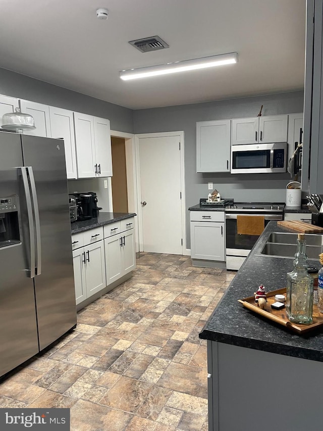 kitchen with appliances with stainless steel finishes, sink, and white cabinets