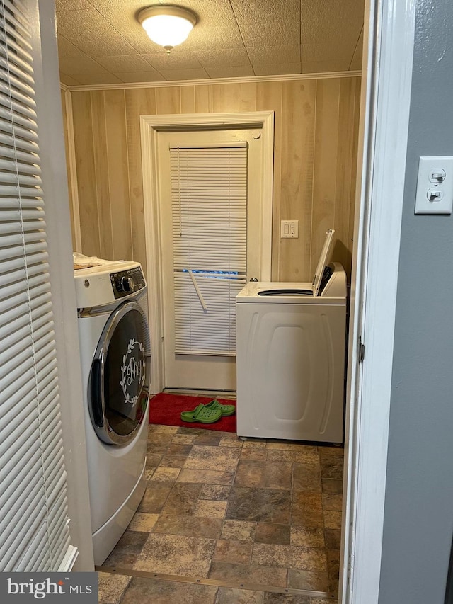 washroom with washer / clothes dryer, crown molding, and wood walls