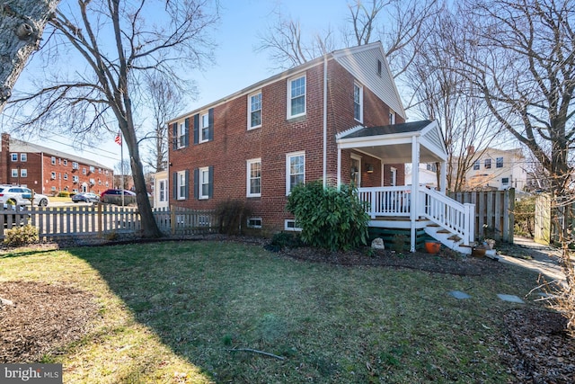 view of property exterior featuring a yard, fence, a porch, and brick siding