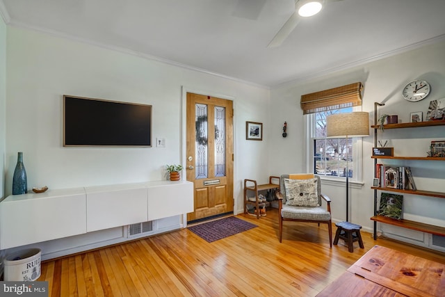 living area with ceiling fan, hardwood / wood-style flooring, and crown molding