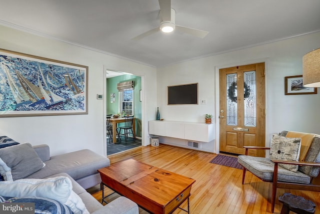 living area with crown molding, visible vents, ceiling fan, and hardwood / wood-style floors