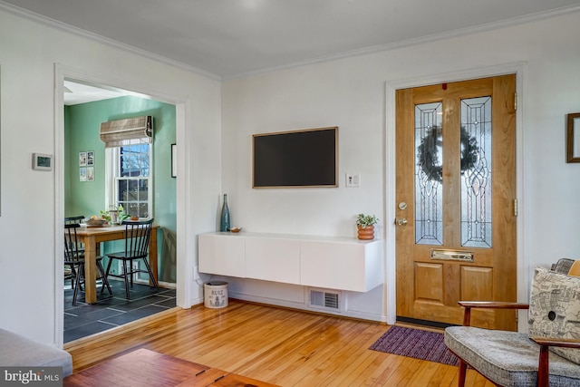 interior space with ornamental molding, baseboards, visible vents, and hardwood / wood-style floors