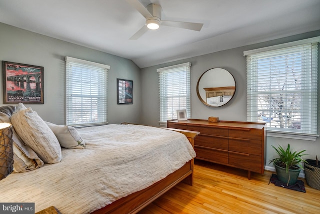 bedroom featuring lofted ceiling, multiple windows, light wood-type flooring, and a ceiling fan