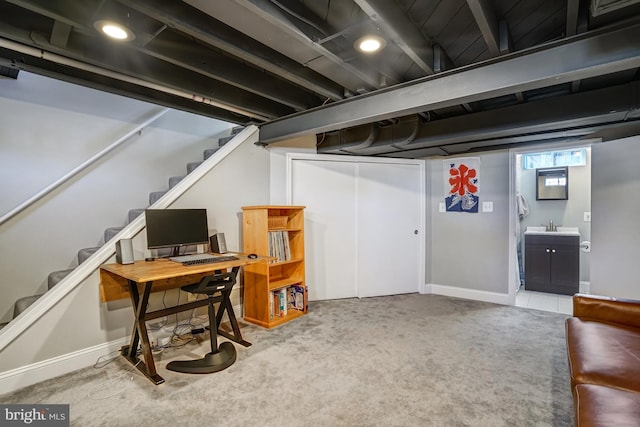 carpeted office space with a sink and baseboards