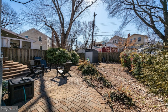 view of patio / terrace with a fenced backyard, an outdoor structure, and a storage unit