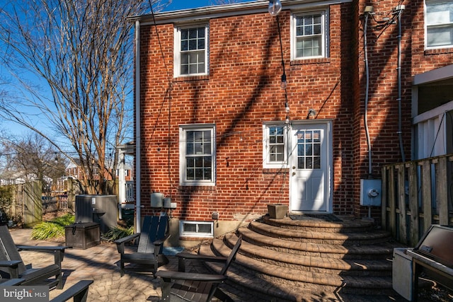 back of property featuring brick siding, a patio area, and fence