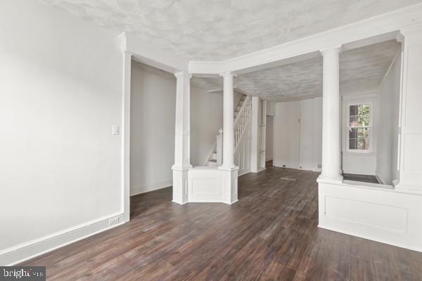 spare room with dark hardwood / wood-style flooring and ornate columns