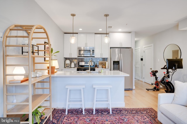 kitchen featuring decorative light fixtures, stainless steel appliances, light countertops, decorative backsplash, and white cabinets