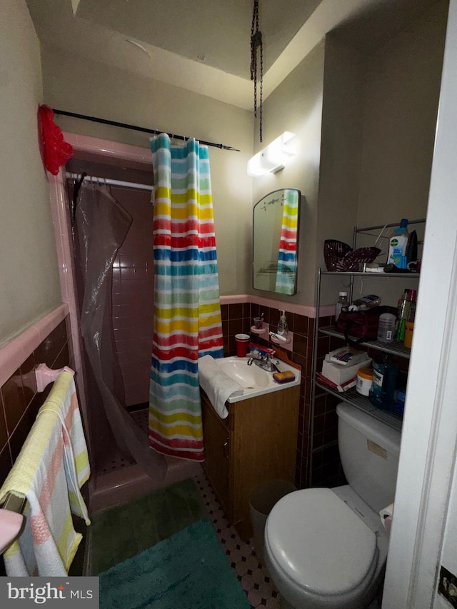 bathroom with tile walls, vanity, toilet, and walk in shower