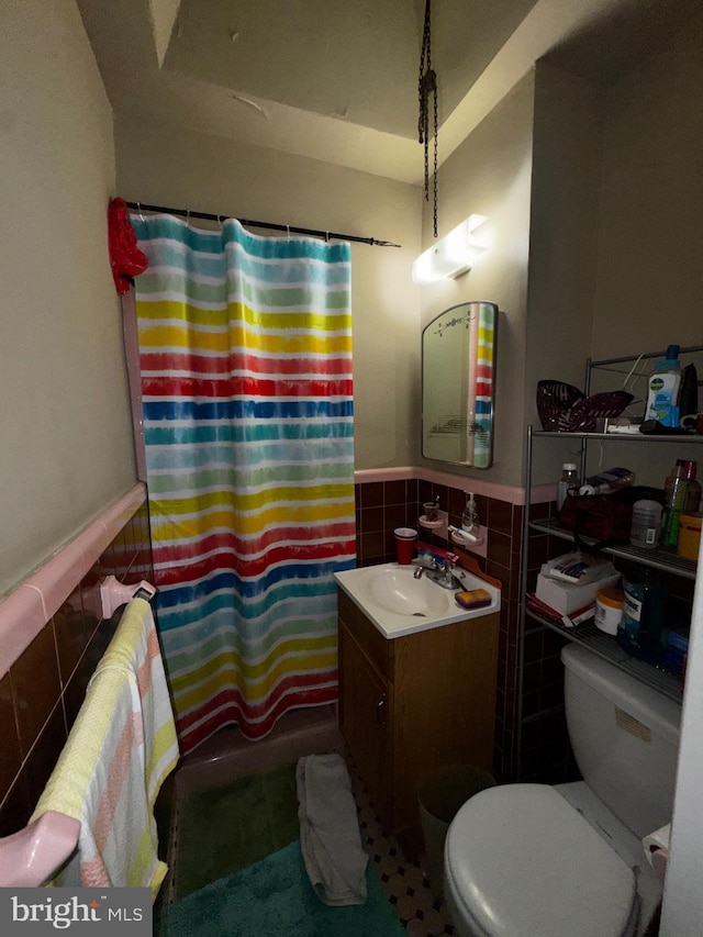 full bathroom featuring toilet, vanity, shower / bathtub combination with curtain, and tile walls