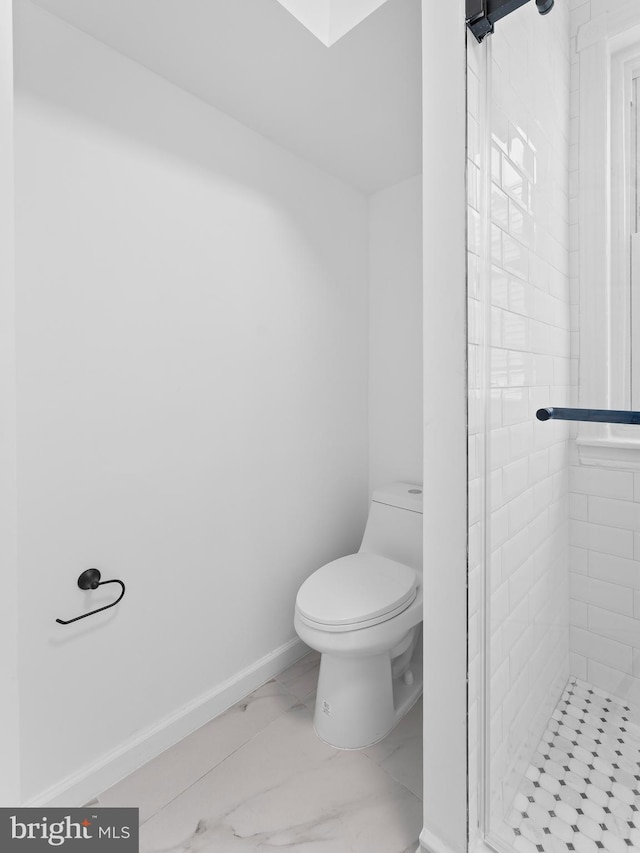 bathroom with a tile shower and toilet