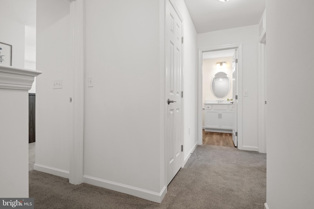 corridor featuring sink and light colored carpet