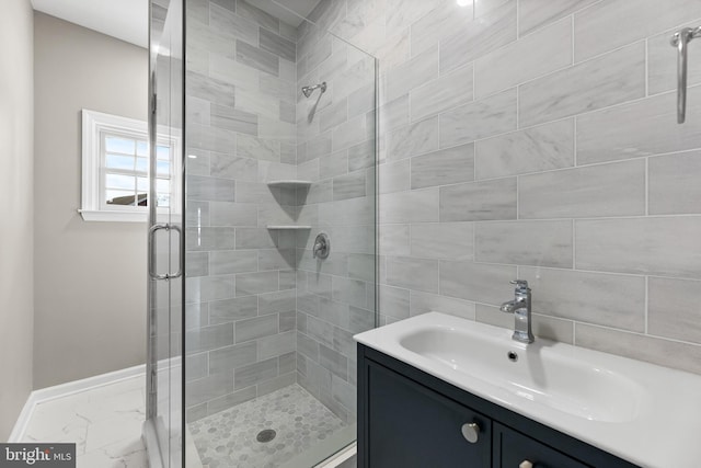 bathroom with marble finish floor, baseboards, a shower stall, and vanity