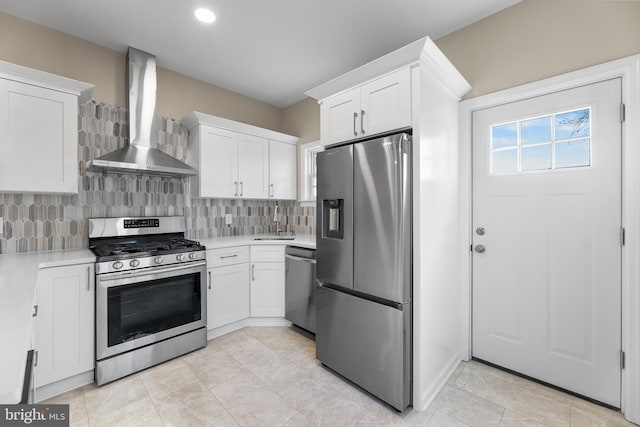 kitchen featuring wall chimney range hood, white cabinetry, appliances with stainless steel finishes, and light countertops