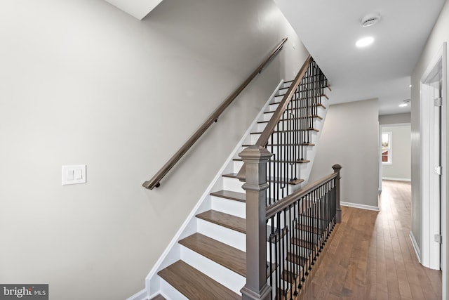 stairway with baseboards, wood finished floors, and recessed lighting