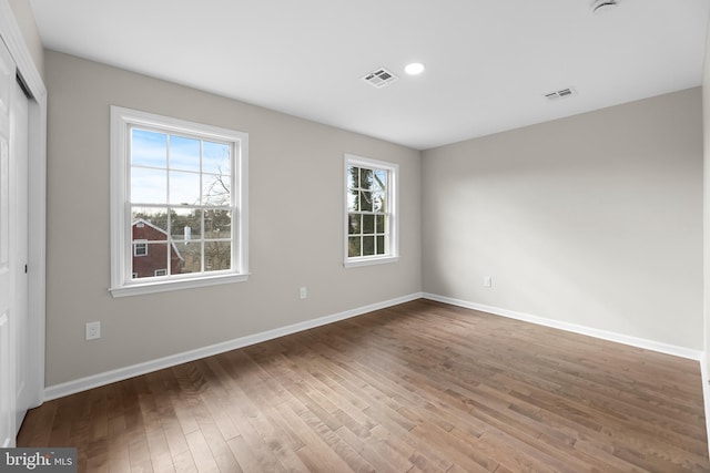 empty room featuring recessed lighting, visible vents, baseboards, and wood finished floors