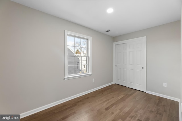 unfurnished bedroom with baseboards, a closet, visible vents, and wood finished floors