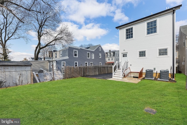 back of house with a fenced backyard, a lawn, and cooling unit