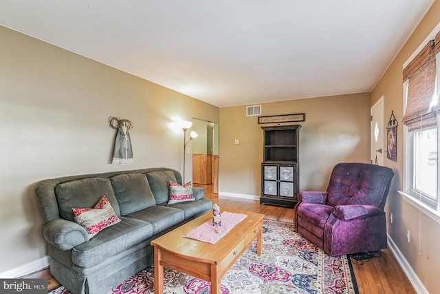 living area featuring wood finished floors, visible vents, and baseboards