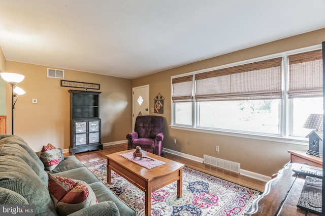 living area featuring visible vents, baseboards, and wood finished floors