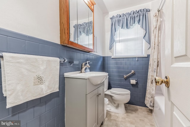 bathroom featuring a wainscoted wall, tile walls, toilet, shower / bath combo with shower curtain, and vanity