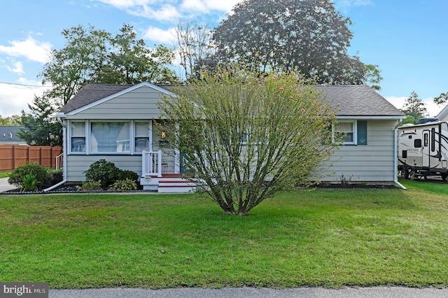 view of front of property with a front yard, fence, and roof with shingles