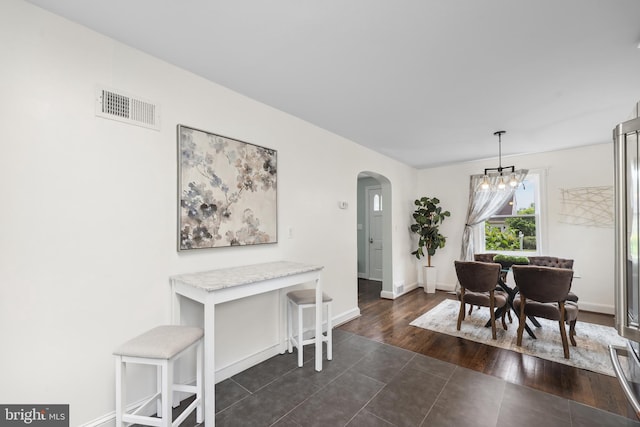 507 Janneys Ln, Alexandria, VA 22302 - dining area with arched walkways, a chandelier, dark tile patterned floors, and baseboards