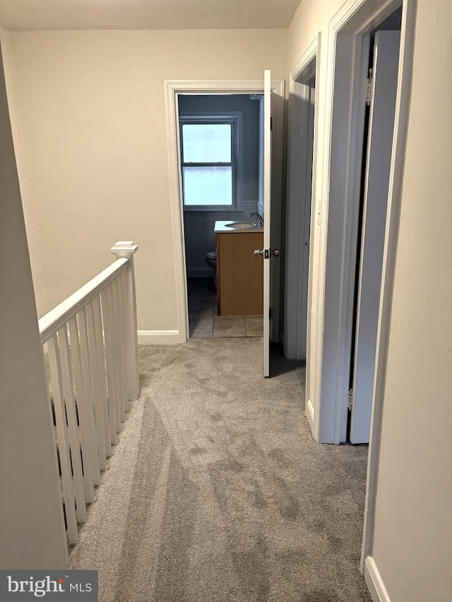 hall with sink and light carpet