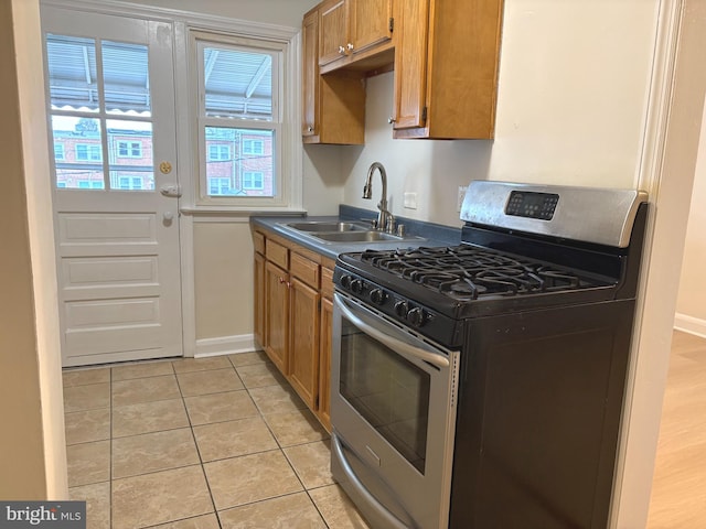 kitchen featuring stainless steel range with gas cooktop, sink, and light tile patterned floors