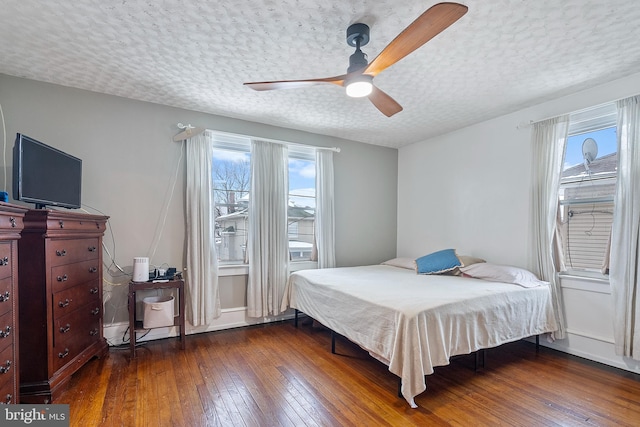 bedroom with dark wood-type flooring, ceiling fan, multiple windows, and a textured ceiling