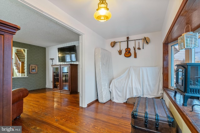 interior space with brick wall, dark hardwood / wood-style flooring, and a textured ceiling