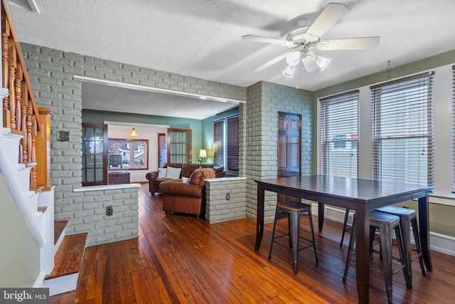 dining room with ceiling fan, dark wood-type flooring, and a textured ceiling