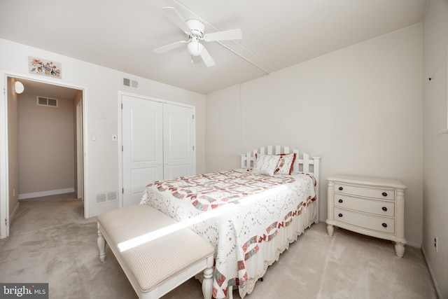 bedroom with light colored carpet, ceiling fan, and a closet