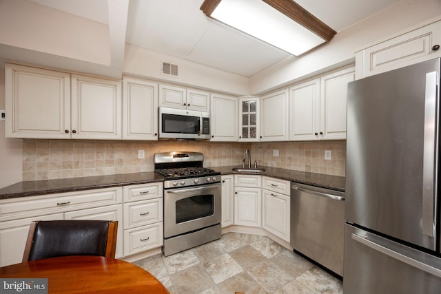 kitchen with dark stone countertops, sink, white cabinets, and appliances with stainless steel finishes