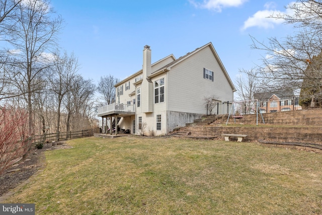 back of property featuring a lawn, a wooden deck, and a playground