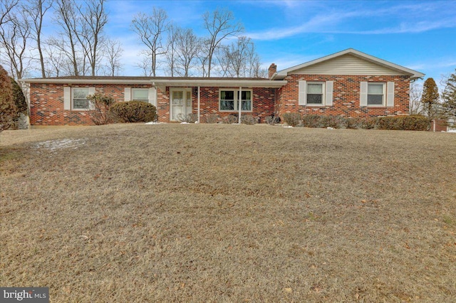 ranch-style house featuring brick siding, a front lawn, and a chimney