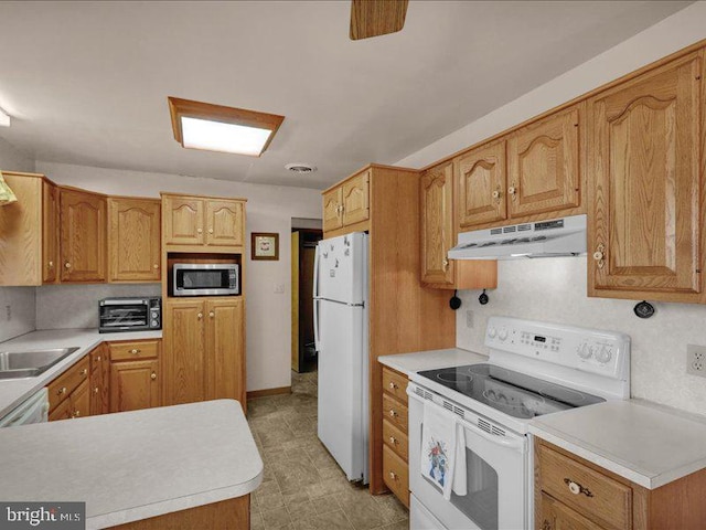 kitchen with light countertops, white appliances, a sink, and under cabinet range hood