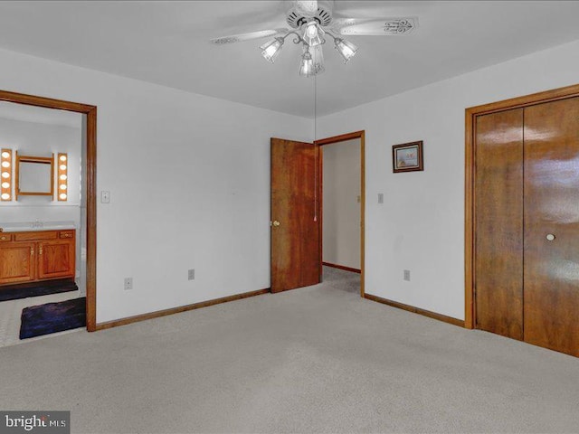 unfurnished bedroom with a closet, a ceiling fan, light carpet, a sink, and baseboards