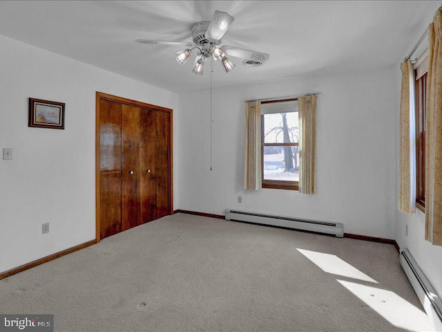 unfurnished bedroom with a baseboard radiator, a closet, baseboards, and carpet