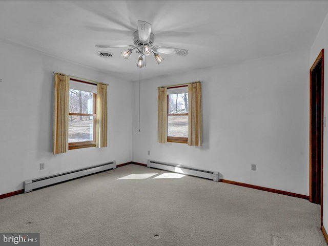 spare room with carpet, visible vents, baseboard heating, and a ceiling fan