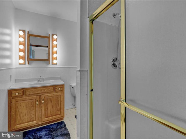 bathroom featuring a wainscoted wall, toilet, a shower stall, vanity, and tile patterned floors