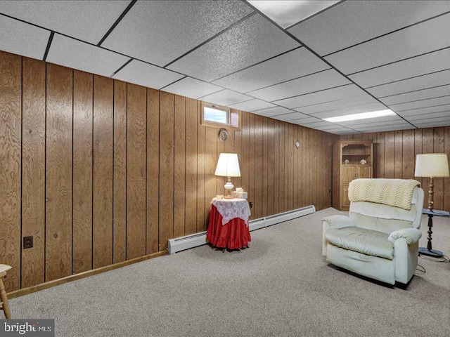 unfurnished room featuring wood walls, a drop ceiling, baseboard heating, and carpet flooring