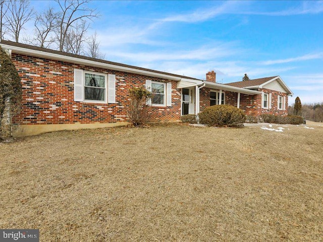 ranch-style home with a chimney, a front lawn, and brick siding