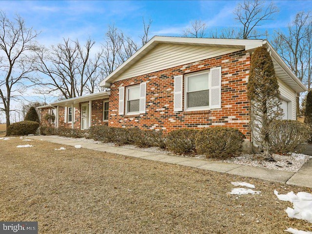 view of front facade with a garage, a front yard, and brick siding