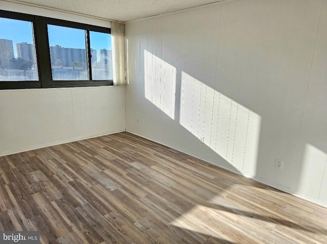 unfurnished room featuring wood-type flooring and a textured ceiling