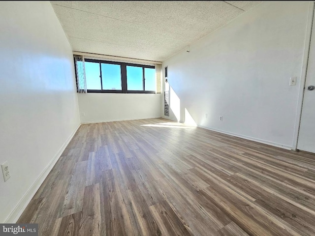 unfurnished room with a textured ceiling and hardwood / wood-style flooring