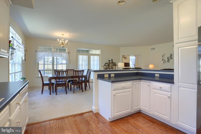 kitchen with an inviting chandelier, white cabinetry, and light hardwood / wood-style flooring