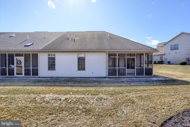 rear view of property with a lawn and a sunroom