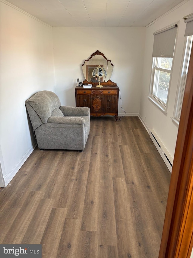 living area with a baseboard heating unit, dark wood-style flooring, and baseboards